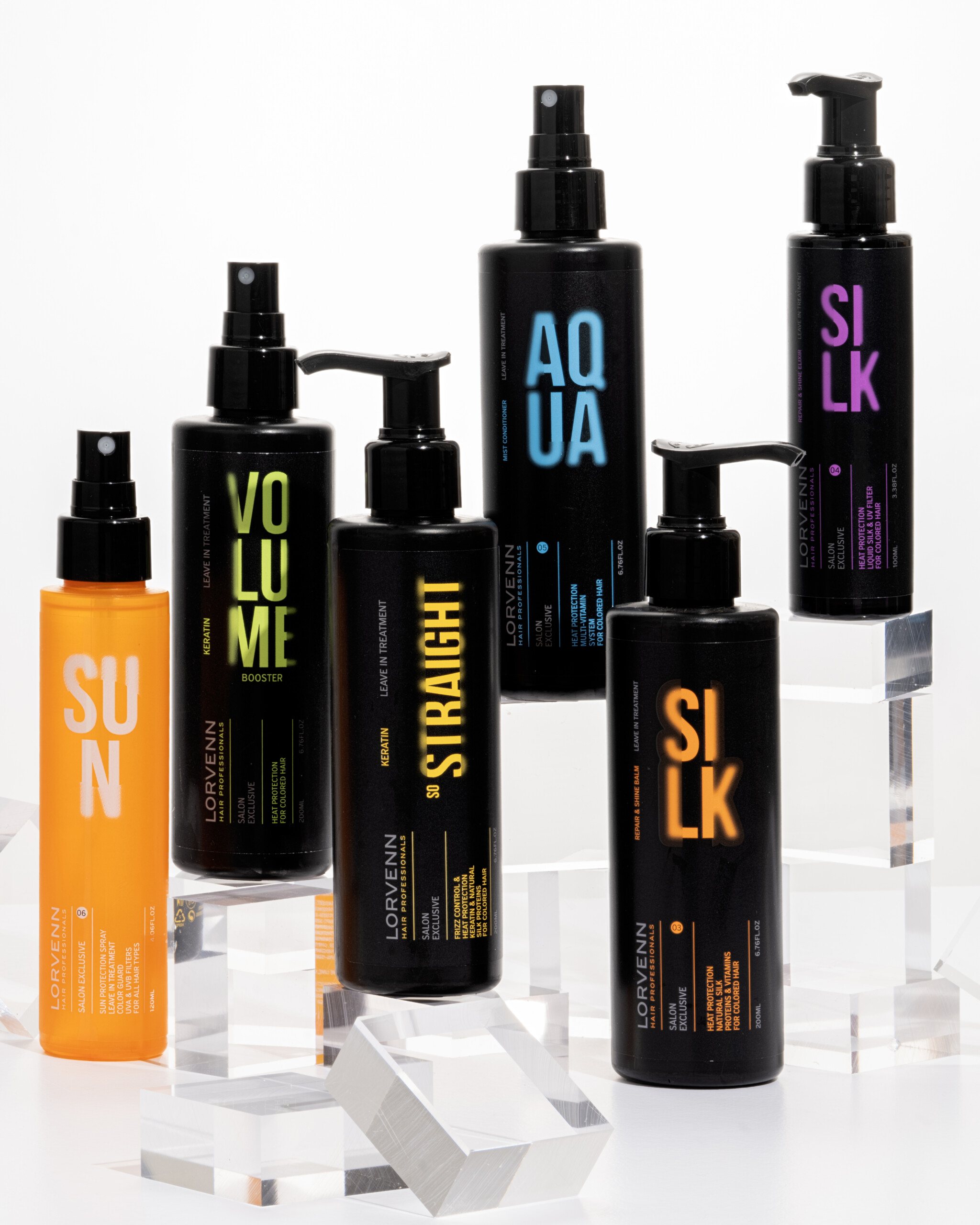 An assortment of black and orange Lorvenn hair care bottles arranged on clear geometric blocks against a white background.